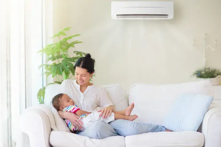 mother and child on couch below a ductless unit