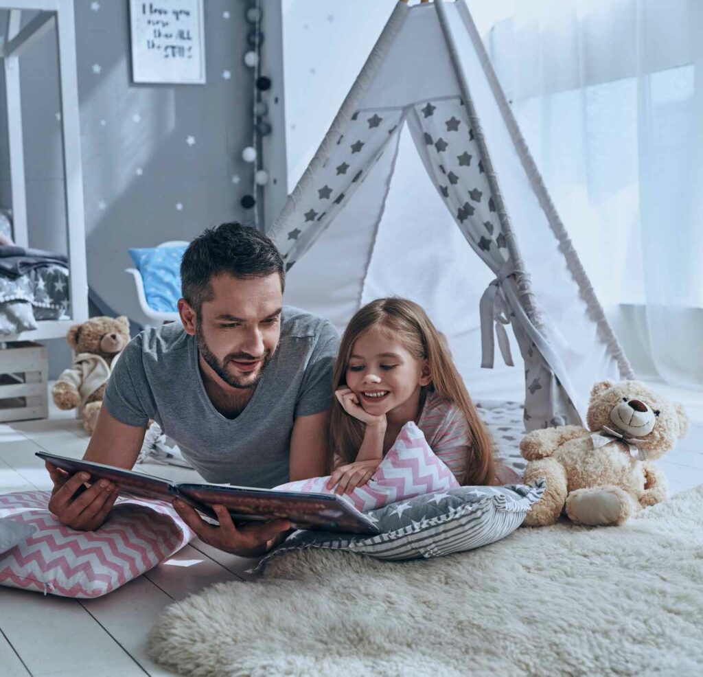 father and daughter reading a book inside home