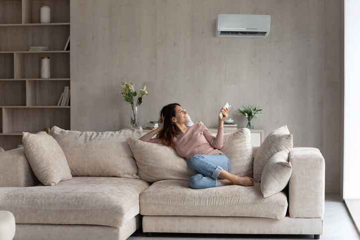 woman operating HVAC unit from couch